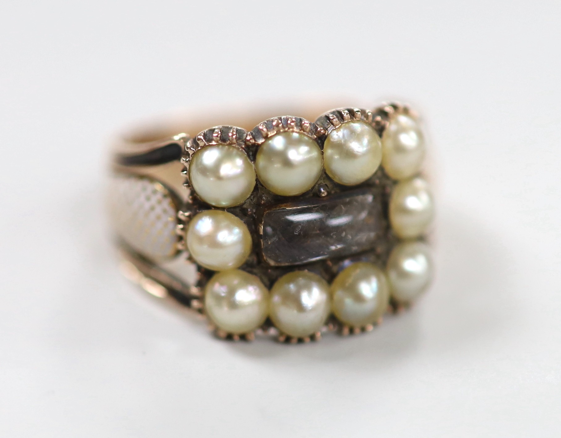 A 19th century yellow metal, plaited hair, enamel and split pearl set mourning ring, size P, gross weight 5.3 grams